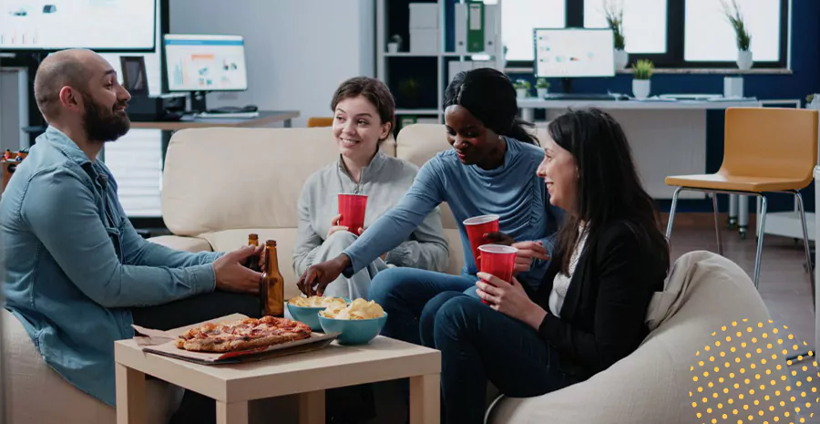 imagem de quatro pessoas sentadas ao redor de uma mesa conversando, bebendo e comendo