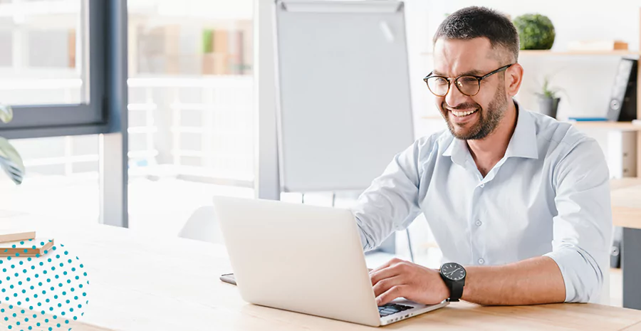 imagem de um homem sentado na frente de um computador sorrindo