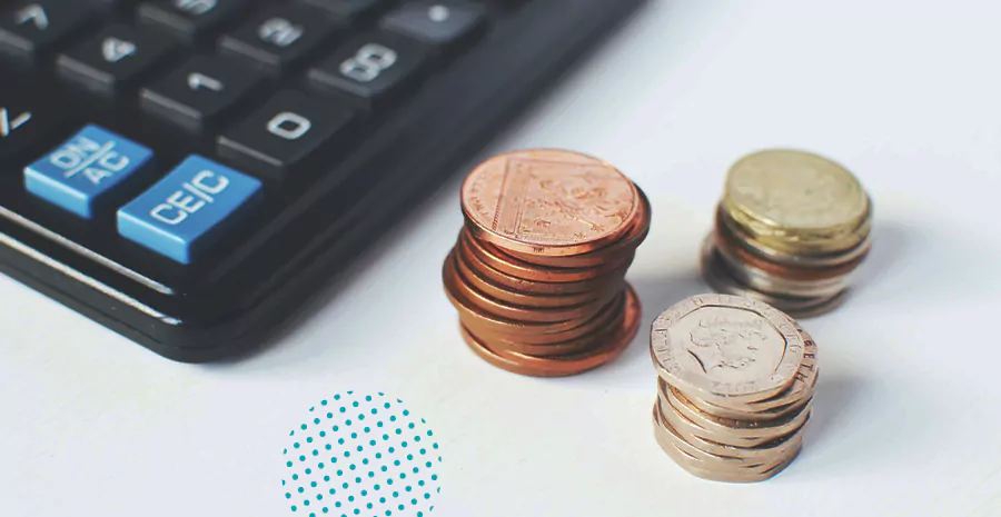 imagem de três pilhas de moedas ao lado de uma calculadora