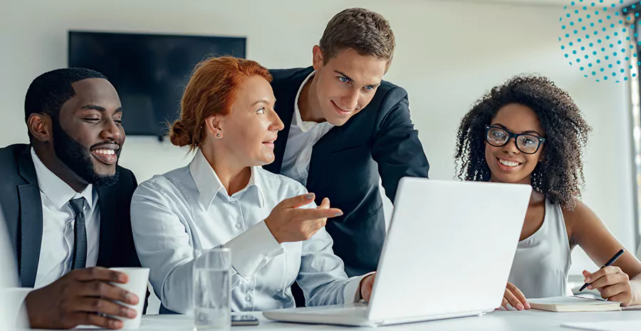 imagem de duas mulheres e dois homens sentados na frente de um computador sorrindo e conversando