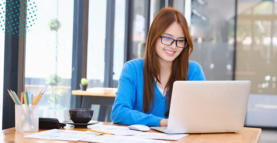 imagem de uma mulher sorrindo sentada na frente de um computador