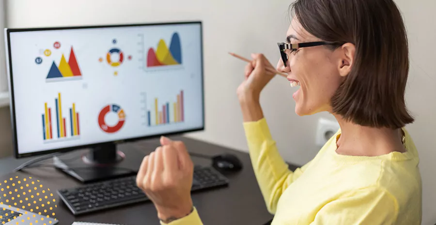 imagem de uma mulher sorrindo sentada na frente de um computador e vendo gráficos