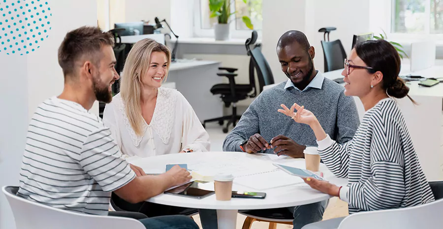 imagem de duas mulheres e dois homens sentados ao redor de uma mesa sorrindo e conversando