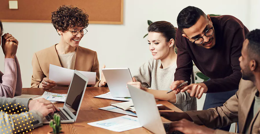 imagem de um grupo de pessoas ao redor de uma mesa mexendo em computadores