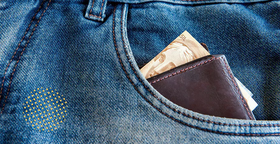 imagem de uma carteira com uma nota de dinheiro dentro de um bolso de uma calça jeans