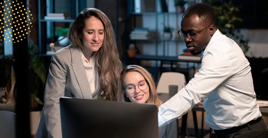 imagem de duas mulheres e um homem olhando para um computador