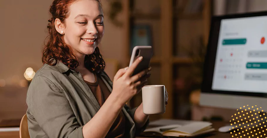 imagem de uma mulher sorrindo segurando uma xícara e um celular