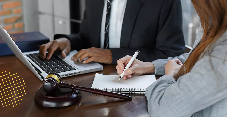 imagem de um homem sentado digitando em um computador e uma mulher sentada escrevendo em um caderno