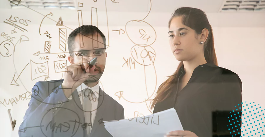 Um homem e uma mulher observando gráficos em uma lousa