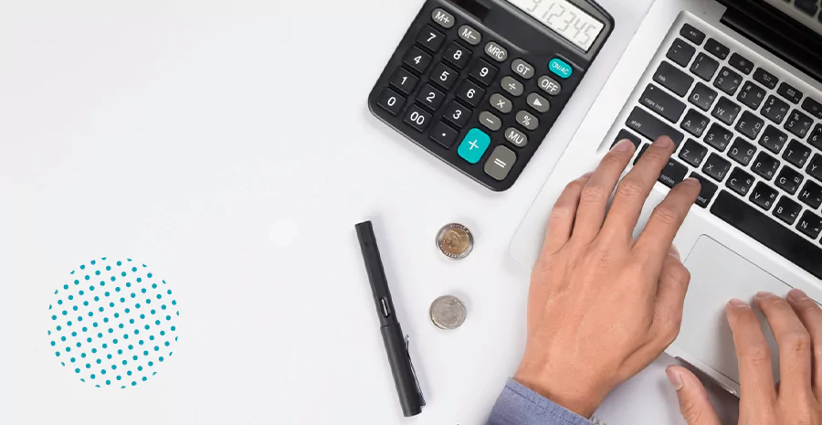 Um homem mexendo em um notebook ao lado da calculadora