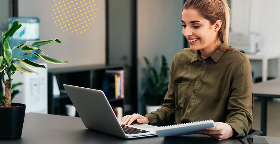 Uma mulher sorrindo utilizando um notebook