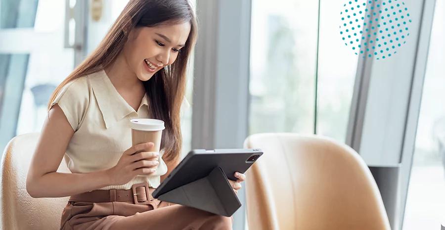 Mulher segurando um tablet enquanto toma um café