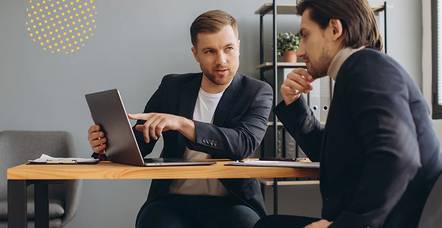 Dois homens observando um notebook, representando o fluxograma de demissão