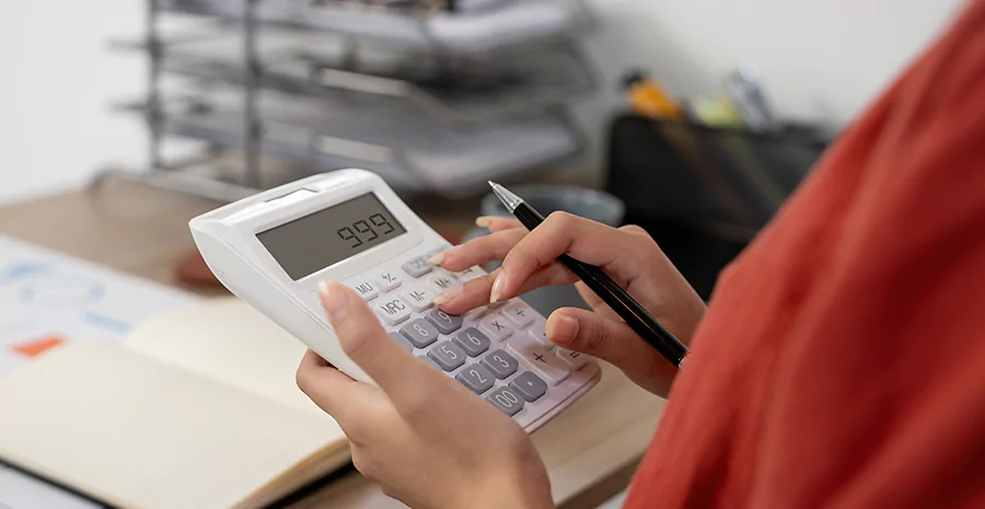 pessoa com uma calculadora e uma caneta nas mãos