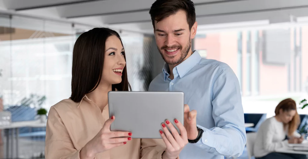 Homem e mulher conversando enquanto seguram um tablet