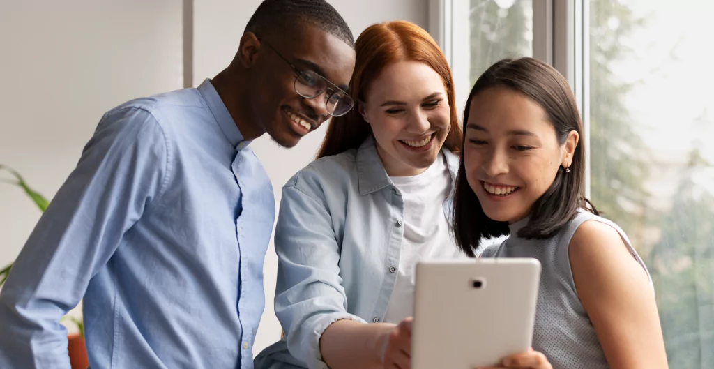 Três pessoas observando um tablet