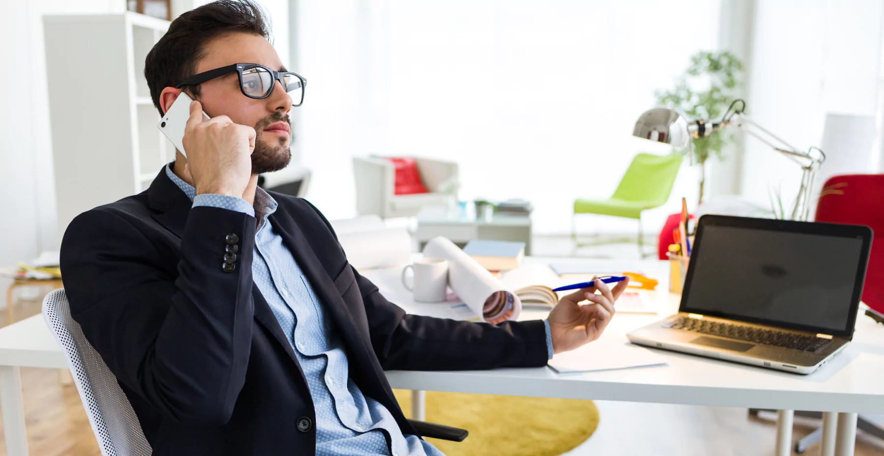 homem sentado em uma mesa de escritório falando no telefone 