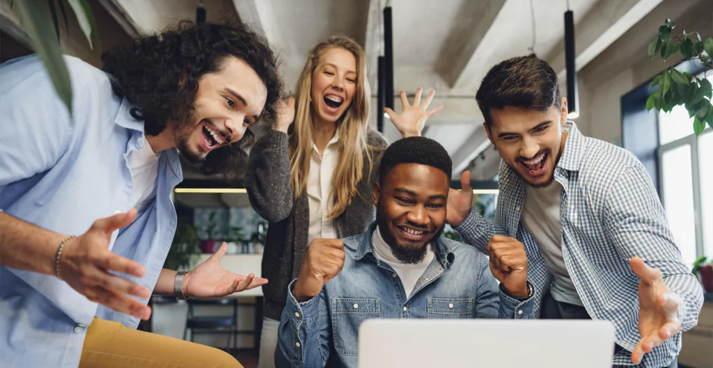 Várias pessoas comemorando em frente a um computador