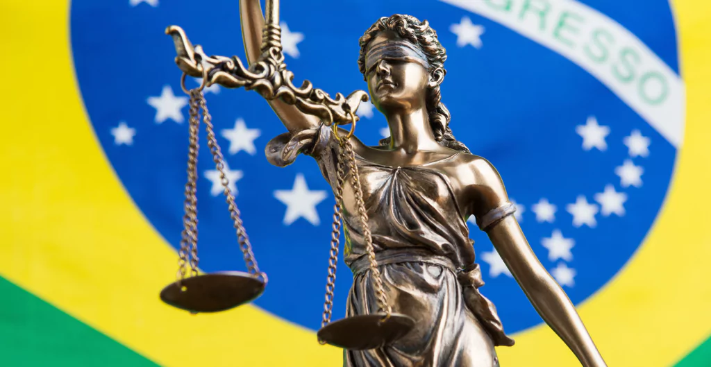 A estátua da justiça segurando a balança em frente à bandeira do brasil