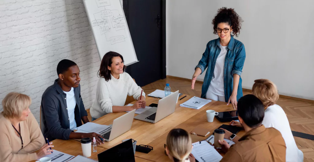 Um grupo de pessoas sentadas em torno de uma mesa com laptops
