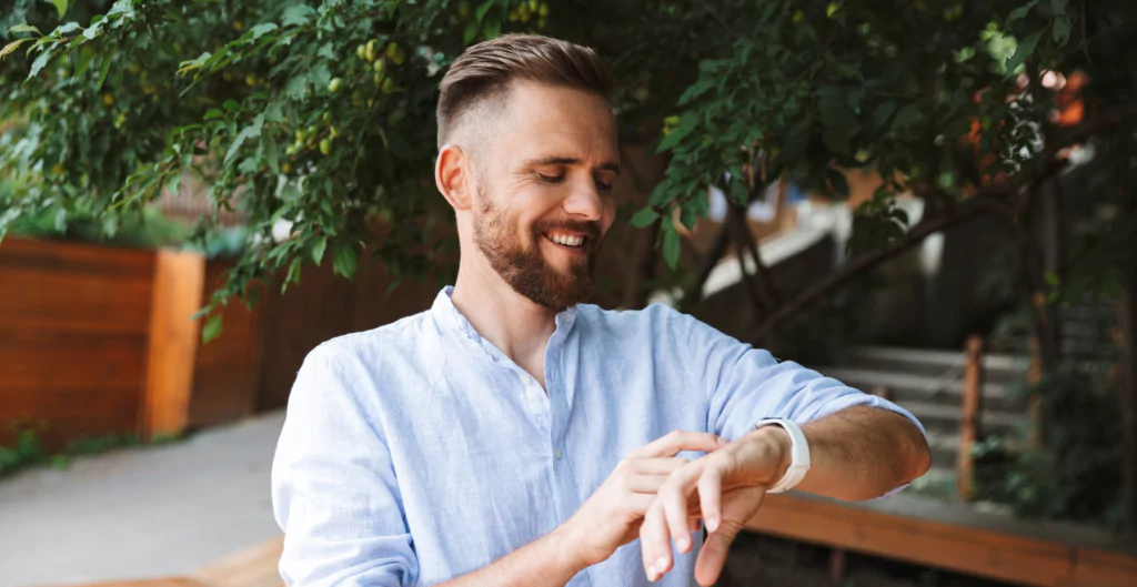 Um homem vestindo uma camisa azul e olhando para seu relógio