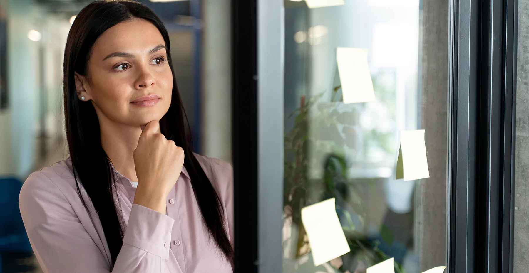 mulher olhando para um vidro com post its com expressão de pensativa