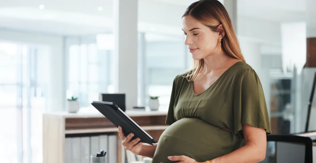 Uma mulher grávida está olhando para um tablet