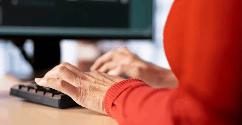 mãos digitando em teclado, com suéter vermelho