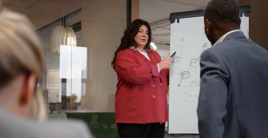 mulher apresentando desenho de gráficos feios em um quadro branco em uma sala de reuniões