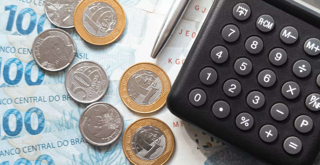 Calculadora e caneta sobre a mesa sugerem cálculo de salário.
