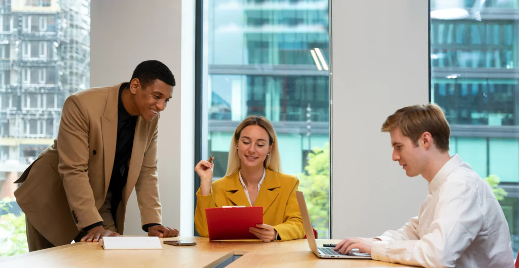 Equipe reunida em uma mesa de escritório, discutindo projetos e colaborando.