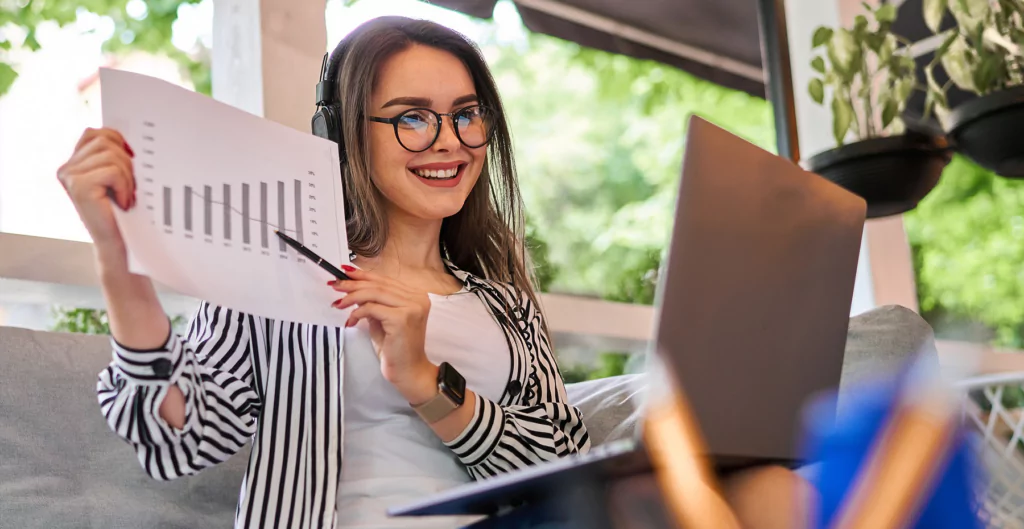 mulher fazendo uma reunião online e ostrando um papel com gráficos