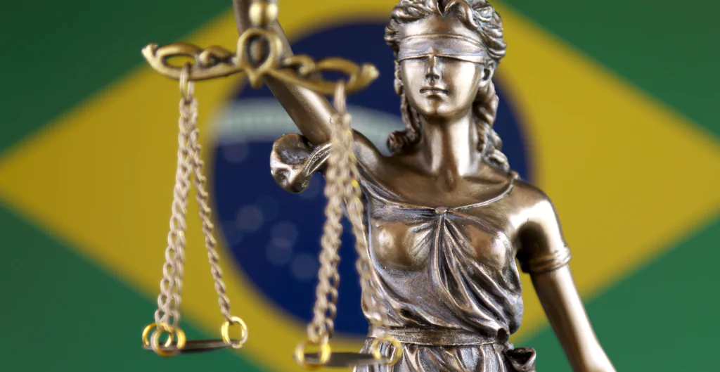 imagem da estátua da deusa da justiça, Têmis, na frente da bandeira do brasil
