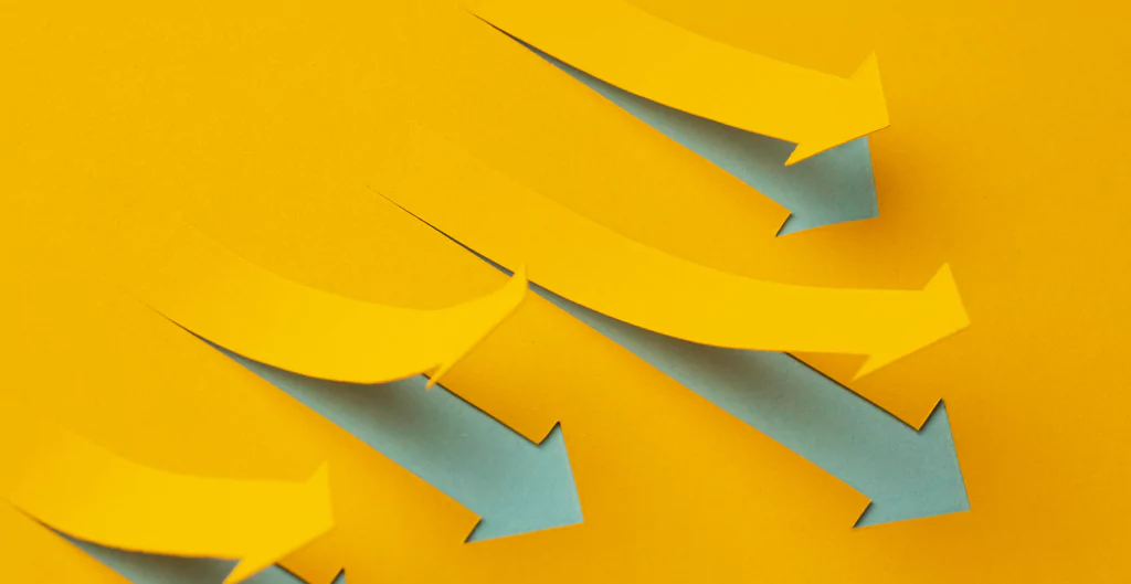 Setas divergentes em papel colorido, simbolizando a diferença entre OKRs e KPIs.