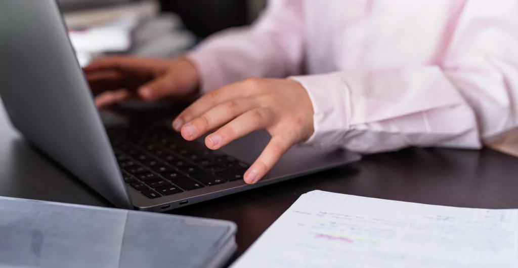Profissional preenchendo formulários e analisando informações no laptop, representando o processo de rescisão e recolhimento do FGTS.