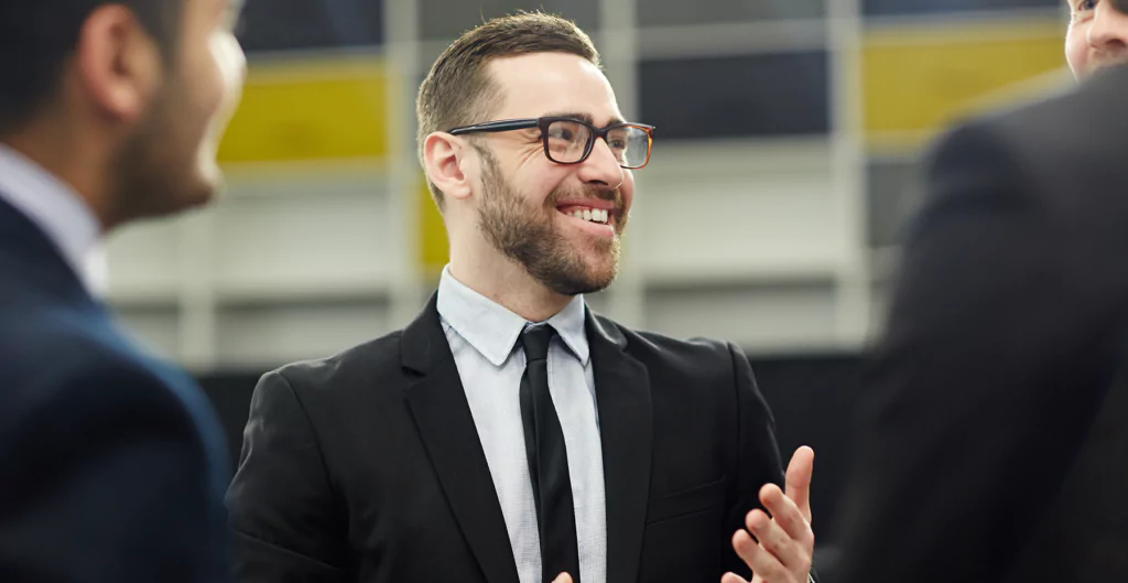 homem sorridente usando um terno e em um ambiente corporativo