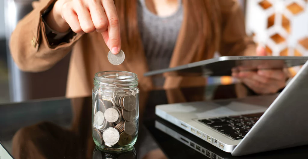 mulher depositando moedas em um cofrinho de plastico transparente