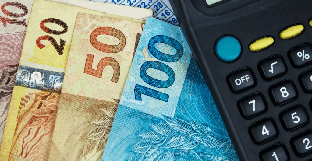 Notas de cem, cinquenta, vinte e dez reais com calculadora o lado