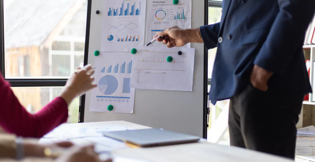 Reunião de negócios com apresentação de gráficos e dados estatísticos em ambiente de escritório.