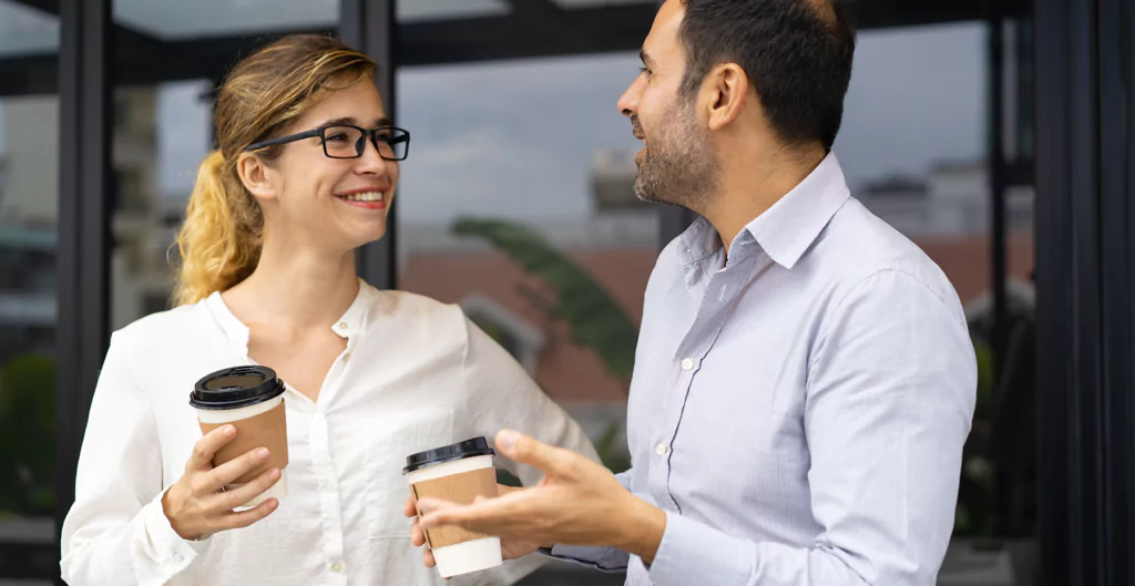 Homem e mulher conversando com copos de café nas mãos