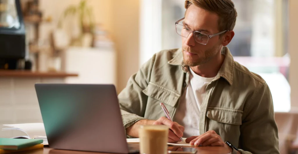 Homem concentrado em tarefas no laptop, indicando produtividade no retorno de férias.