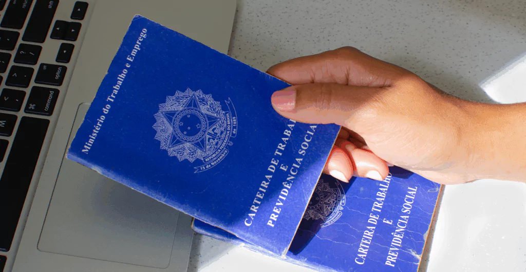 Carteira de trabalho sobre notebook, representando registro e gestão de férias.