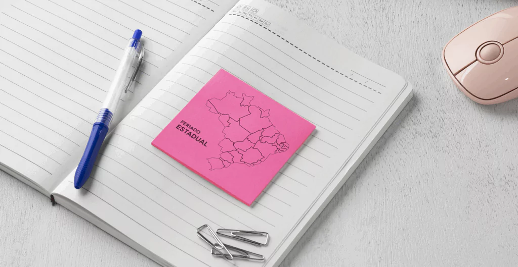 post-it rosa, com o mapa do Brasil, sobe um caderno, com caneta e clipes ao lado