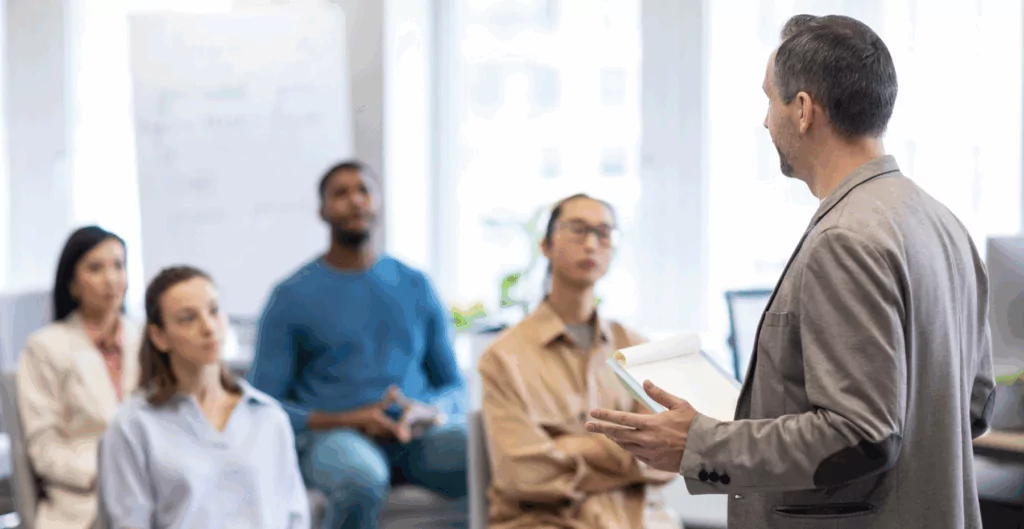 Homem de terno participando de uma reunião de negócios com colegas de equipe em sala de conferências.
