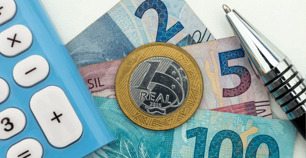Close‑up de uma calculadora, uma caneta e dinheiro, relacionado a Programa de remuneração.
