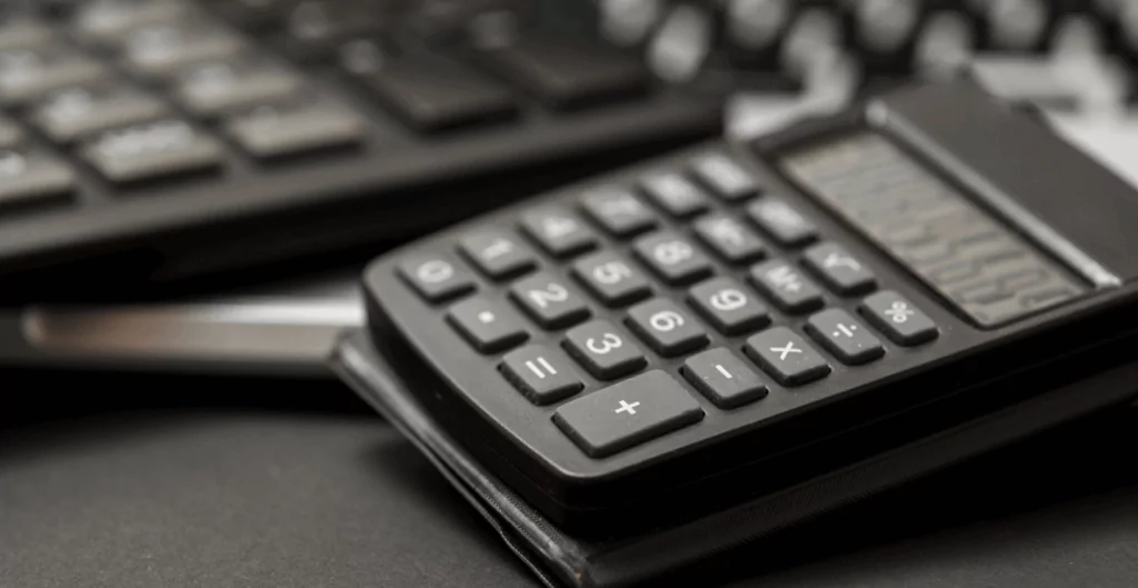 Uma calculadora e um teclado sobre a mesa, no contexto de Programa de remuneração.