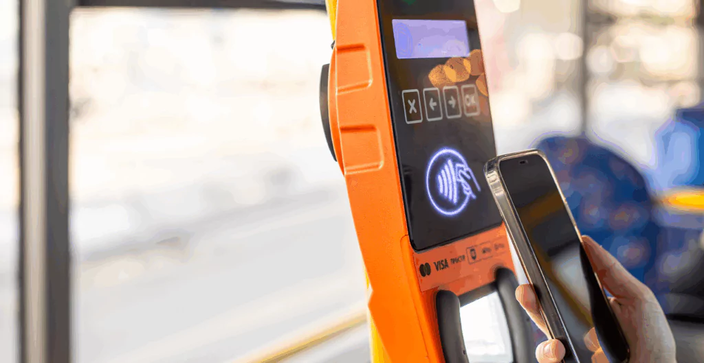 Pessoa usando o celular com vale transporte digital para pagamento por aproximação no novo terminal de cartão de transporte, destacando a inovação em métodos de pagamento.