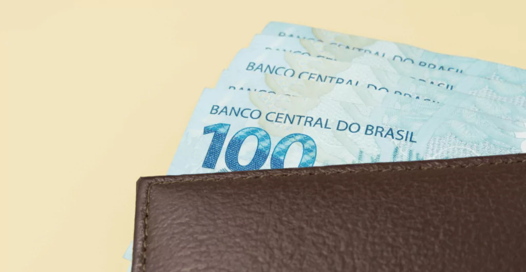 Notas de cem reais em uma carteira de couro, ilustrando a liquidez oferecida pelo adiantamento depositante.