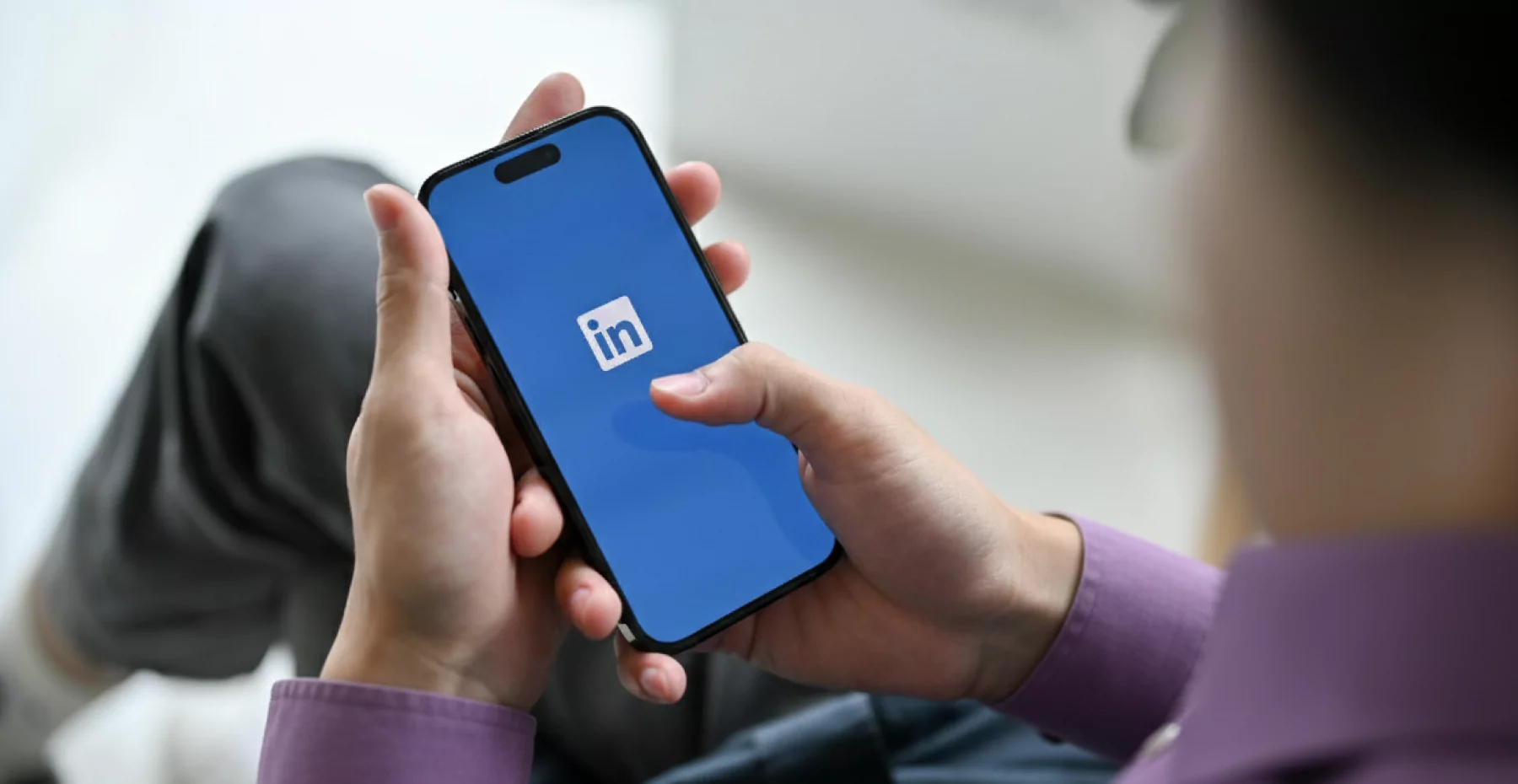 Homem abrindo o aplicativo no celular, demonstrando como usar o LinkedIn de forma prática para a gestão da sua carreira.