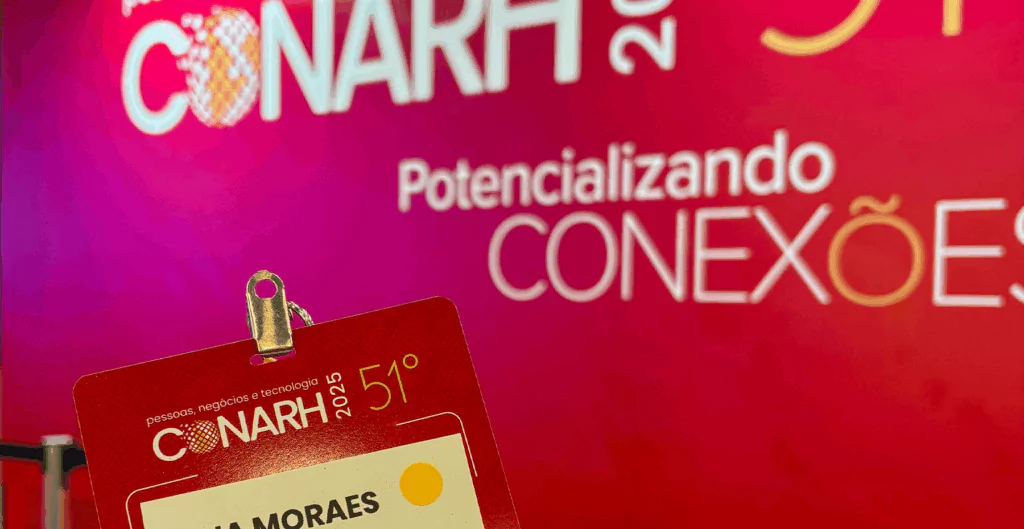 Parede vermelha escrito Potencializando conexões e crachá do evento ConaRH 2025